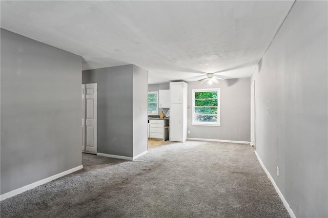 unfurnished living room with light colored carpet and ceiling fan