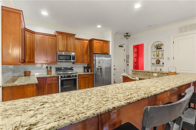 351 NE Washington Ave NE Unit 307, Marietta, GA 30060 - kitchen featuring appliances with stainless steel finishes, a breakfast bar, tasteful backsplash, brown cabinets, and ornamental molding