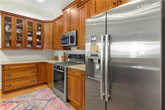 351 NE Washington Ave NE Unit 307, Marietta, GA 30060 - kitchen featuring stainless steel appliances, light stone countertops, glass insert cabinets, brown cabinets, and decorative backsplash