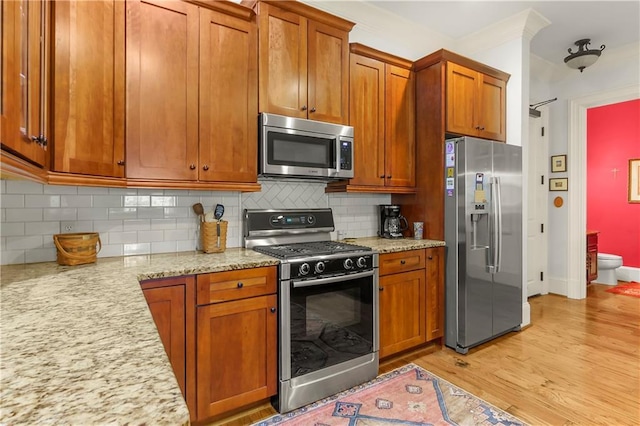 351 NE Washington Ave NE Unit 307, Marietta, GA 30060 - kitchen featuring stainless steel appliances, light wood finished floors, brown cabinets, and crown molding