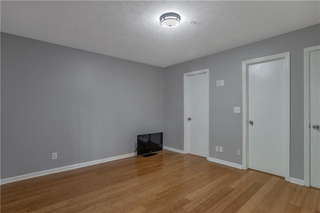 spare room with a textured ceiling and light hardwood / wood-style flooring