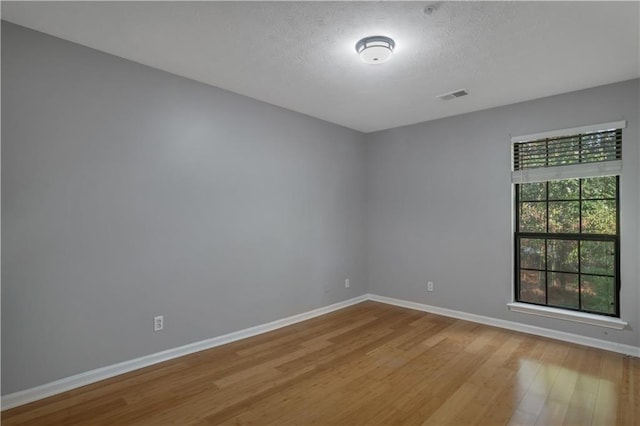 spare room featuring a textured ceiling and light wood-type flooring