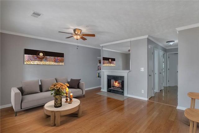 living room with ornamental molding, ceiling fan, and light wood-type flooring