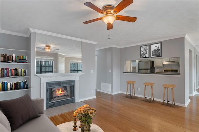 living room featuring crown molding, light hardwood / wood-style flooring, and ceiling fan