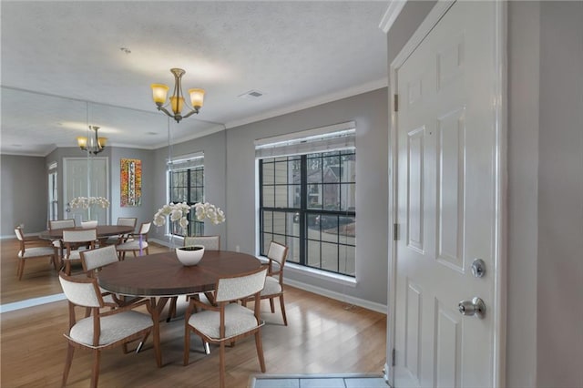 dining space featuring crown molding, a chandelier, and light hardwood / wood-style floors