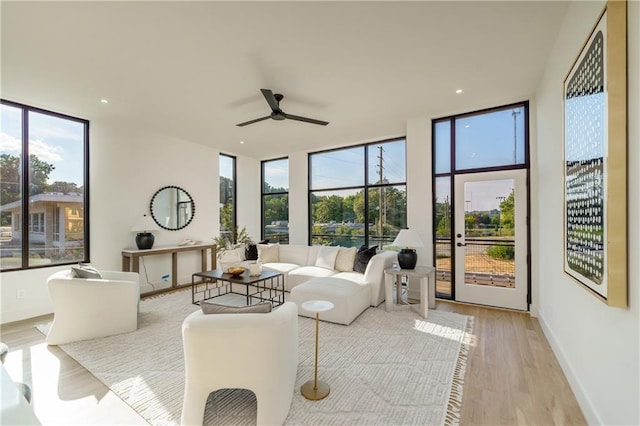 living room featuring ceiling fan, floor to ceiling windows, and light hardwood / wood-style flooring