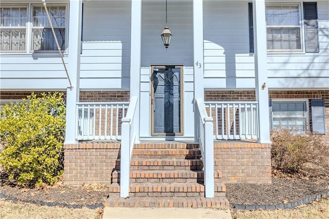 entrance to property featuring covered porch and brick siding