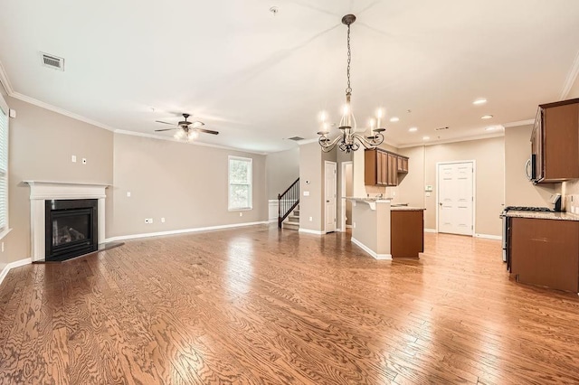 unfurnished living room with hardwood / wood-style floors, ceiling fan with notable chandelier, and crown molding