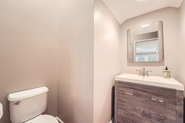 bathroom with vanity, toilet, and vaulted ceiling