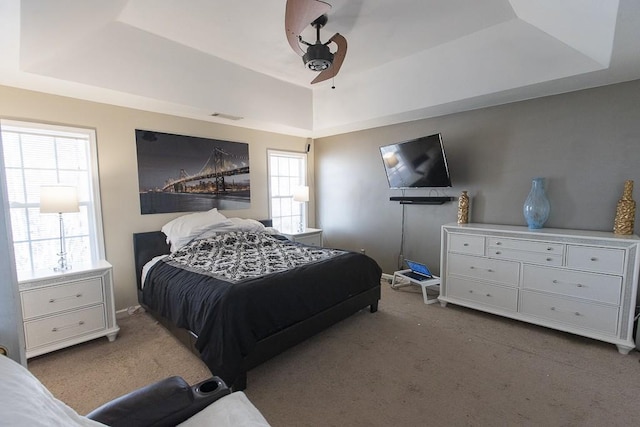 bedroom with carpet flooring, a raised ceiling, and visible vents