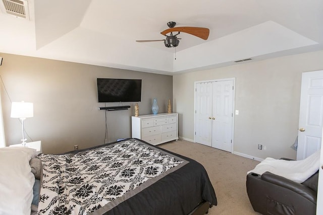 carpeted bedroom featuring a raised ceiling, baseboards, visible vents, and a closet