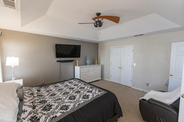 bedroom with a tray ceiling, carpet, visible vents, and baseboards