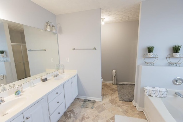 full bathroom featuring double vanity, a stall shower, a textured ceiling, and a sink