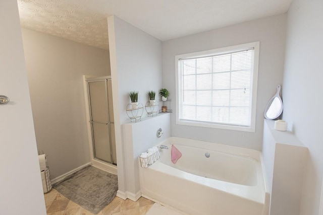 full bathroom with a garden tub, a textured ceiling, a shower stall, tile patterned flooring, and baseboards