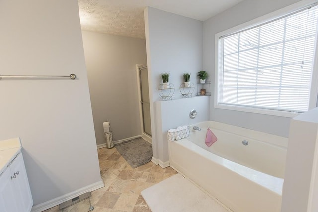 full bath featuring vanity, baseboards, a shower stall, a textured ceiling, and a bath