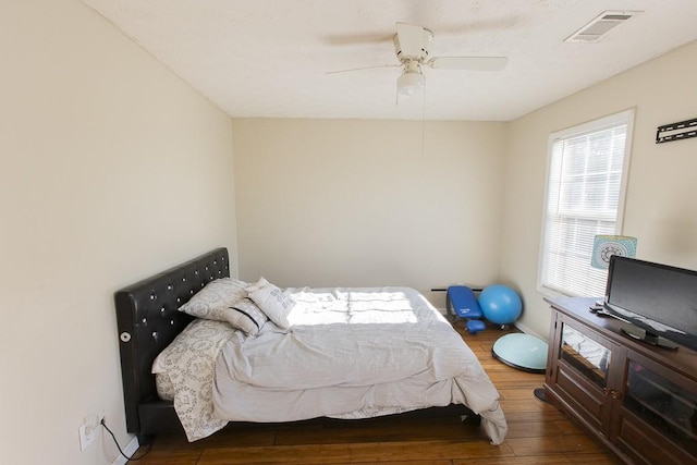 bedroom with ceiling fan, visible vents, and wood finished floors