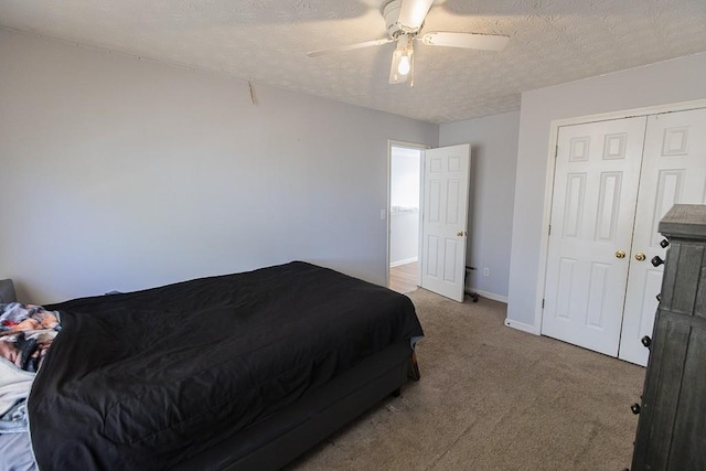 bedroom featuring baseboards, ceiling fan, a closet, a textured ceiling, and carpet flooring