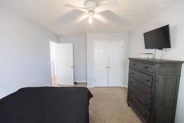 bedroom featuring baseboards, ceiling fan, light colored carpet, a closet, and a textured ceiling