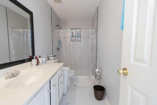 bathroom with toilet, vanity, tiled shower, marble finish floor, and a textured ceiling