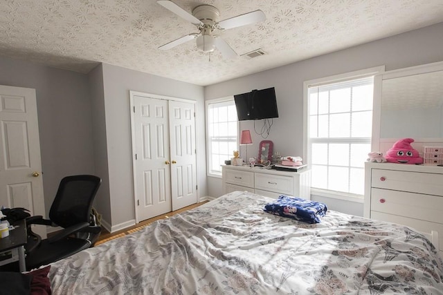 bedroom with baseboards, visible vents, a closet, and a textured ceiling