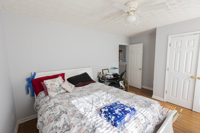 bedroom with ceiling fan, a textured ceiling, baseboards, and wood finished floors