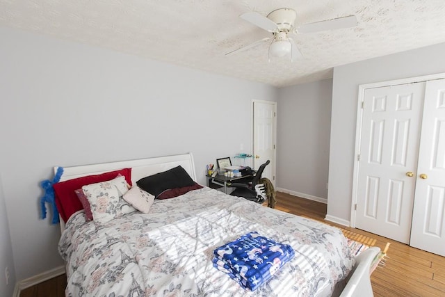 bedroom featuring wood finished floors, baseboards, ceiling fan, a closet, and a textured ceiling