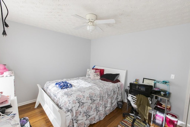 bedroom with a textured ceiling, baseboards, and wood finished floors