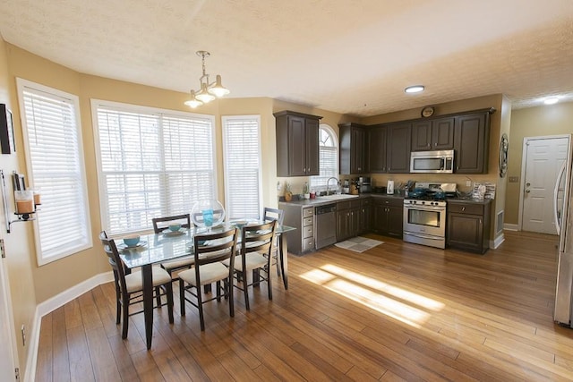 dining space with a notable chandelier, a textured ceiling, baseboards, and hardwood / wood-style floors