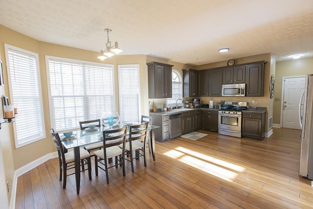 dining room featuring an inviting chandelier, a textured ceiling, light wood-type flooring, and baseboards