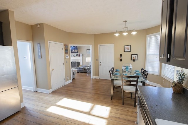 dining area with a fireplace, baseboards, and light wood-type flooring