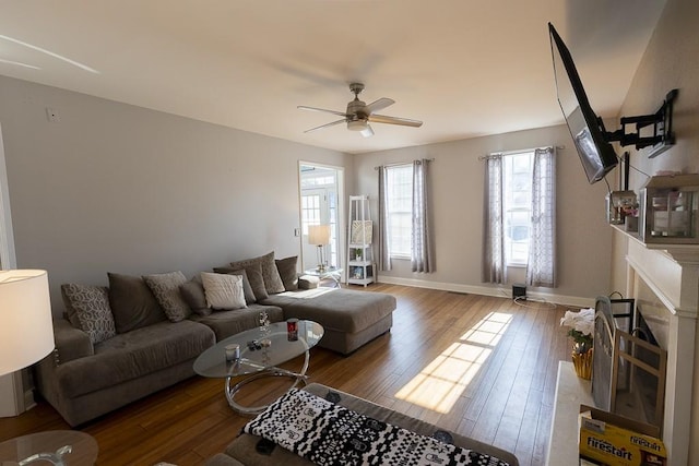 living room with ceiling fan, a fireplace, baseboards, and wood finished floors