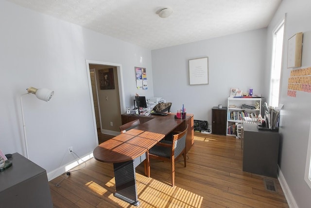 office space featuring baseboards, wood-type flooring, a textured ceiling, and visible vents