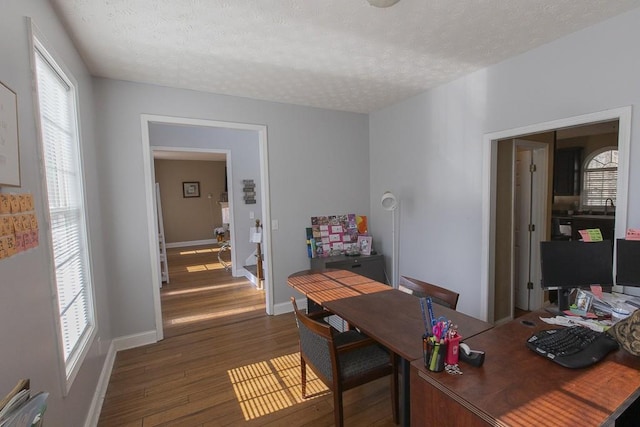 office with a textured ceiling, baseboards, and wood finished floors