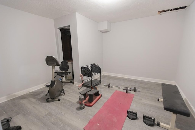 exercise area with wood finished floors, baseboards, and a textured ceiling