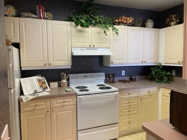 kitchen featuring electric stove, white cabinets, and refrigerator