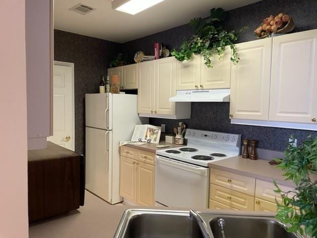 3334 Peachtree Rd NE Unit 1110, Atlanta, GA 30326 - kitchen with under cabinet range hood, light countertops, visible vents, white appliances, and white cabinetry