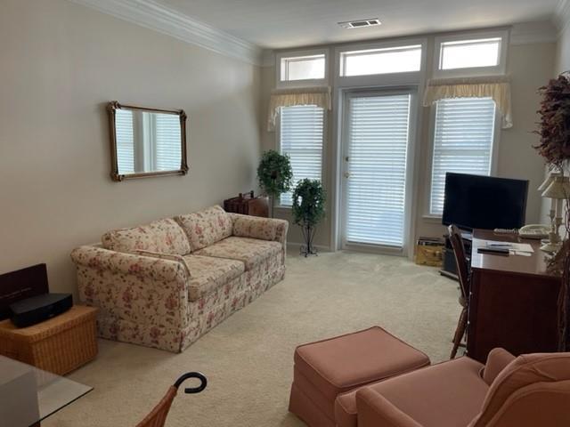 living room with ornamental molding and light colored carpet