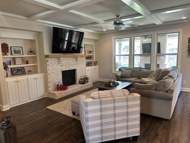 2159 Holland Creek Ln, Buford, GA 30519 - living area featuring dark wood finished floors, a ceiling fan, a brick fireplace, coffered ceiling, and beam ceiling