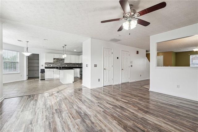 unfurnished living room featuring ceiling fan, a textured ceiling, sink, and dark hardwood / wood-style flooring