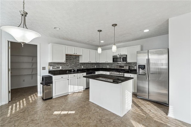 kitchen featuring appliances with stainless steel finishes, a kitchen island, decorative light fixtures, and white cabinetry