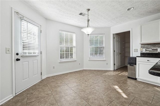 unfurnished dining area featuring light tile patterned floors and a textured ceiling