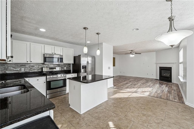 kitchen with pendant lighting, appliances with stainless steel finishes, a center island, and white cabinetry