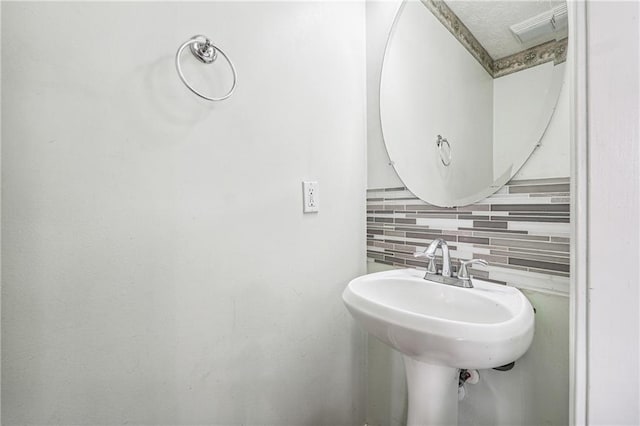 bathroom with decorative backsplash and a textured ceiling