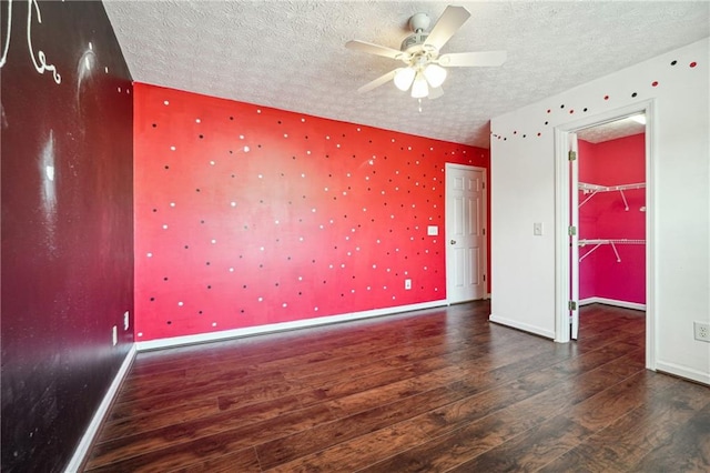 empty room featuring ceiling fan, a textured ceiling, and dark hardwood / wood-style flooring