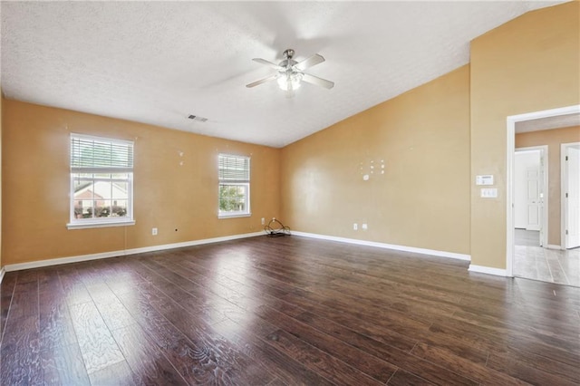 spare room with dark wood-type flooring, ceiling fan, a wealth of natural light, and a textured ceiling