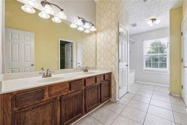 bathroom featuring tile patterned floors, a bathing tub, vanity, and a textured ceiling