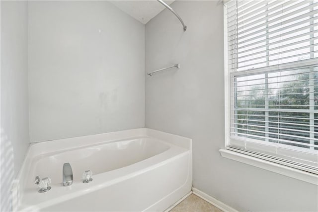 bathroom with a bathing tub, tile patterned flooring, and a wealth of natural light