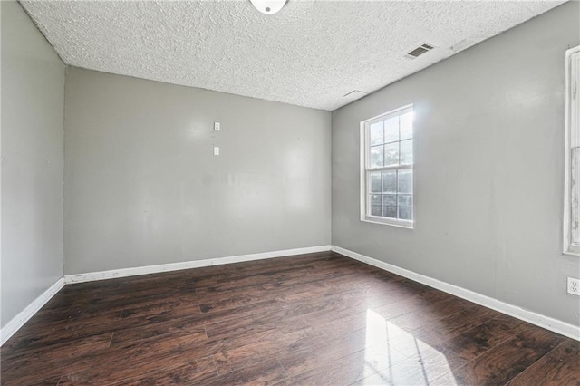 unfurnished room with dark wood-type flooring and a textured ceiling