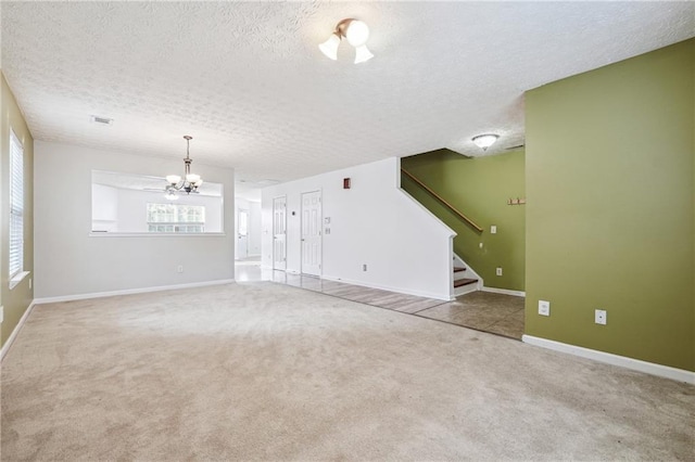 unfurnished living room featuring carpet floors, an inviting chandelier, and a textured ceiling