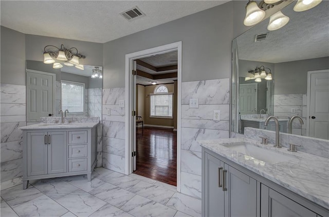 bathroom featuring tile walls, vanity, plenty of natural light, and a textured ceiling